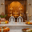 Decorative setup with silver idols, flowers, and candles on a marble surface.