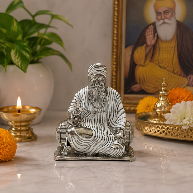 Guru Nanak Dev Ji Brass Idol with Silver Finish seated in meditation pose with Rabab, displayed on home mandir with diya and marigold flowers