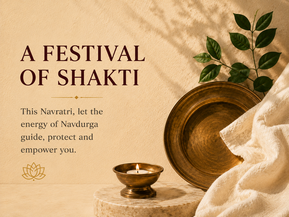 A warm-toned decorative graphic with the text 'A FESTIVAL OF SHAKTI' and a short quote about Navratri. The scene includes a brass plate, a small brass lamp with a lit candle, green leaves, and draped white fabric on a beige textured background.