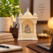 Neem Karoli Baba brass idol with silver finish in a table-top mandir on a desk