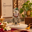 Jagannath Ji murti with silver finish displayed on an office desk beside a laptop