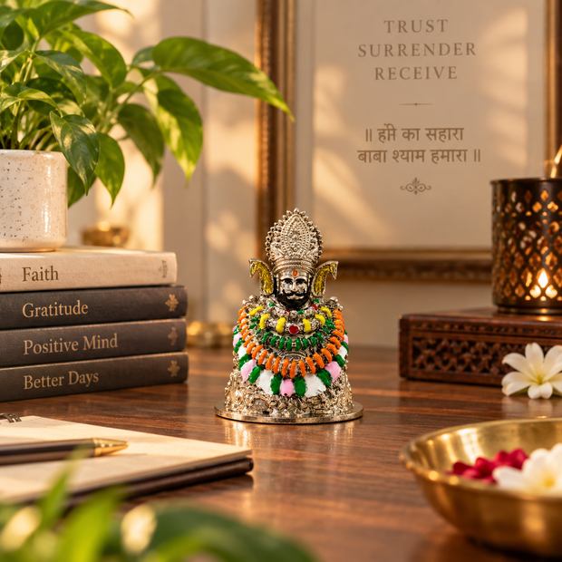 Khatu Shyam Ji murti with silver finish displayed beside a diya and flowers