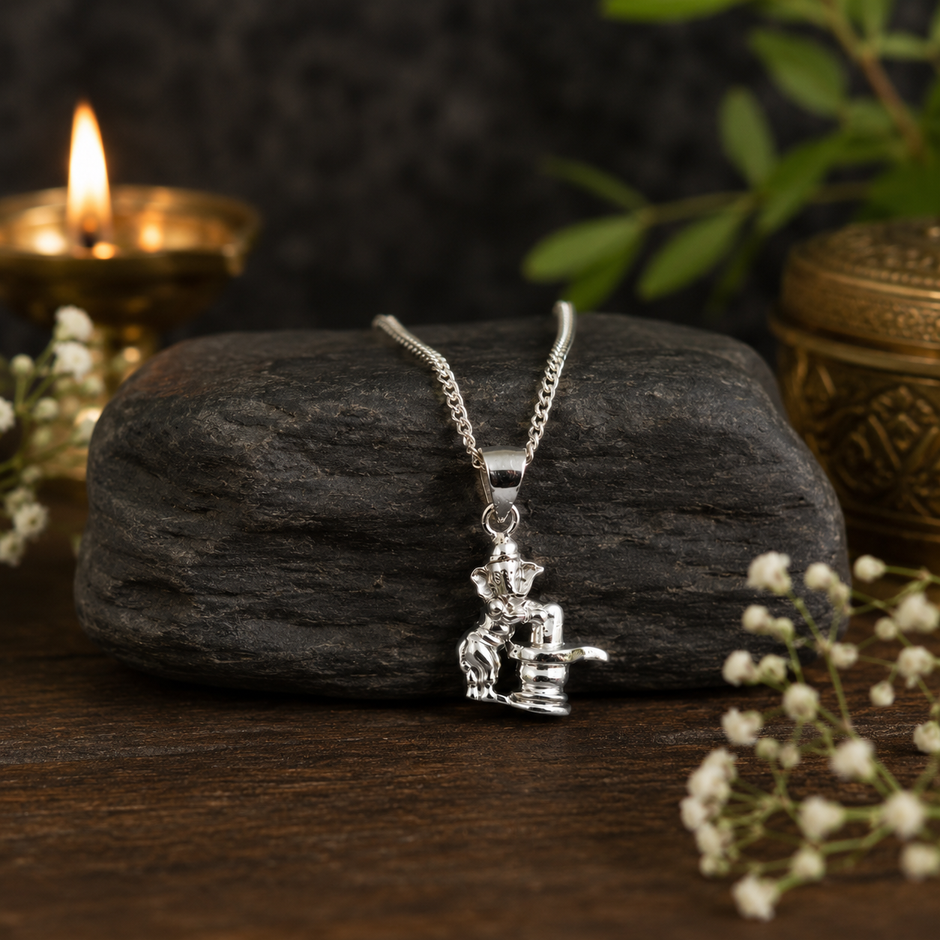 Ganesh Ji with Shivling pendant on dark stone with white flowers and diya
