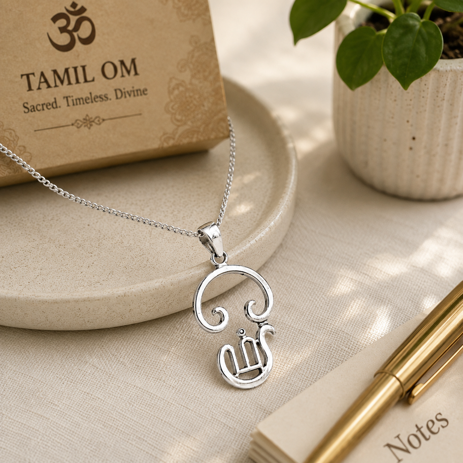 Tamil Om pendant in brass silver finish worn on silver chain displayed on marble plate with diya and Om Namah Shivaya frame in background