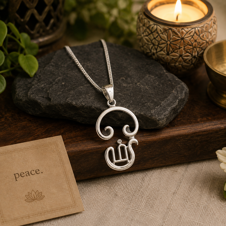 Tamil Om pendant brass silver finish on white ceramic plate with Tamil Om branded box, green plant and pen in background