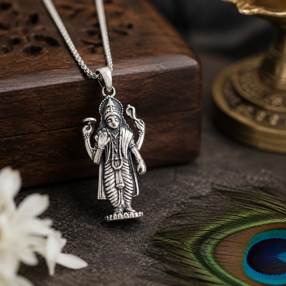 Lord Vishnu Ji pendant in brass silver finish resting against carved wooden block with peacock feather and brass lamp in background