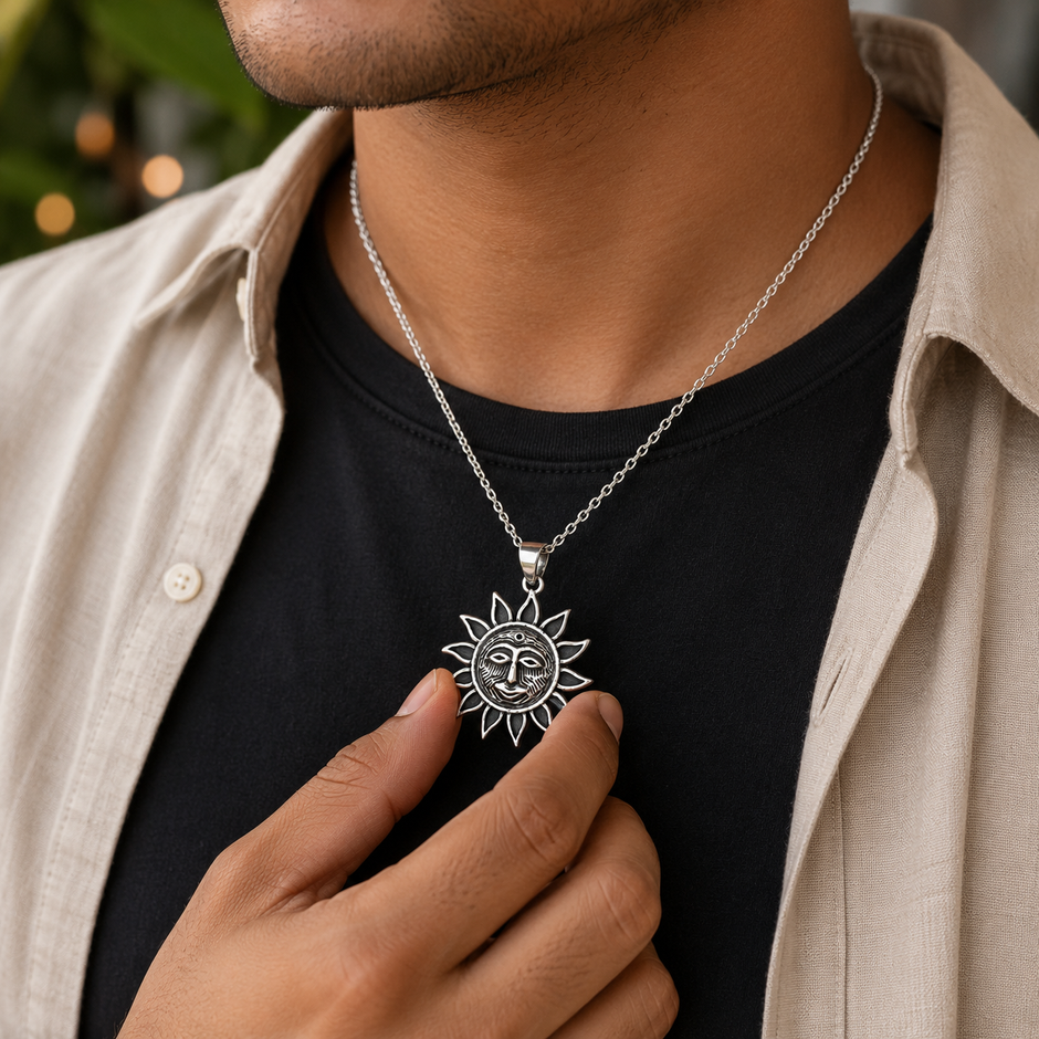 Man in beige linen shirt over black t-shirt holding Surya Dev brass antique silver Sun God pendant on silver chain showing pendant size and style for daily devotional wear