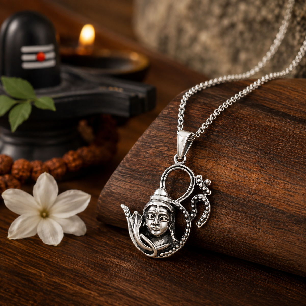 Shiv Ji with OM Brass Pendant on chain on wooden surface with Shivling, diya and white jasmine flower