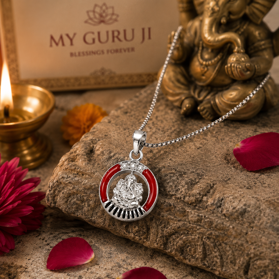 Ganesh Ji brass silver finish pendant with red enamel ring CZ crown and black sunburst rays on silver chain on rough sandstone rock with My Guru Ji branded box, lit brass diya, pink chrysanthemum flower, marigold and red rose petals