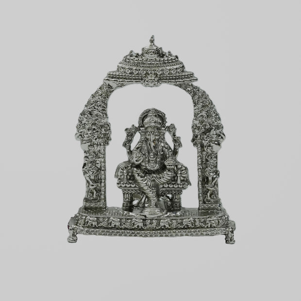My Guru Ji silver-toned metal Lord Ganesha idol seated under an ornate, intricately detailed decorative arch.