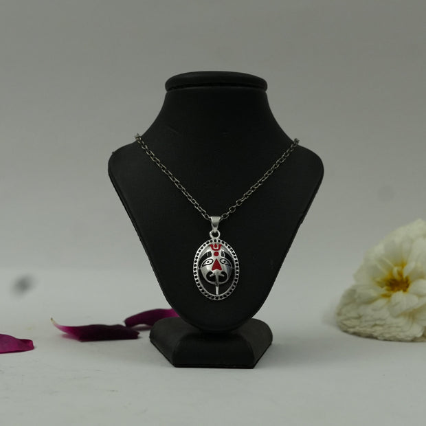 My Guru Ji Sacred Hanuman brass pendant with silver finish and red enamel detailing on a black jewelry display bust.