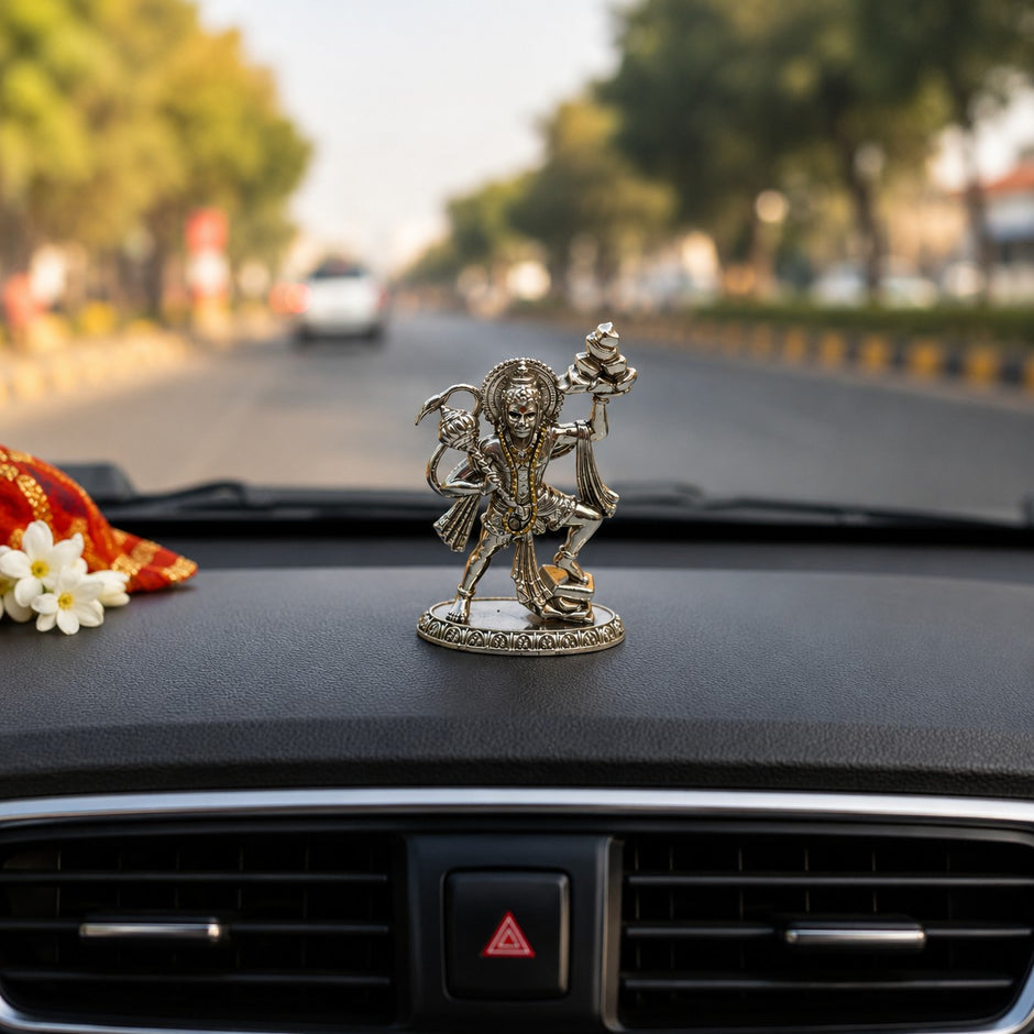 My Guru Ji silver finish brass Veer Hanuman Ji idol carrying Sanjeevani mountain, displayed on a car dashboard.