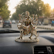 My Guru Ji brass Maa Durga idol with silver finish, seated on a lion, displayed on a car dashboard.