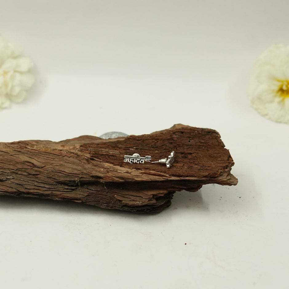 My Guru Ji Mahadev stud earrings in polished silver featuring Hindi script on a rustic wooden surface.