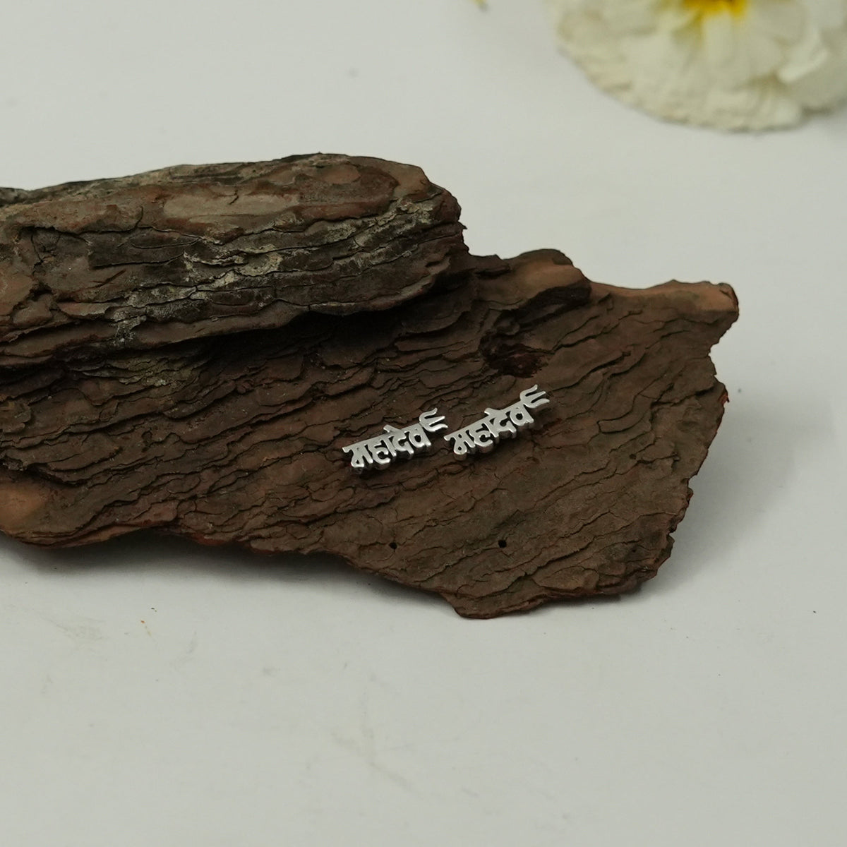 My Guru Ji Mahadev stud earrings in polished silver featuring Hindi script on a rustic wooden bark background.