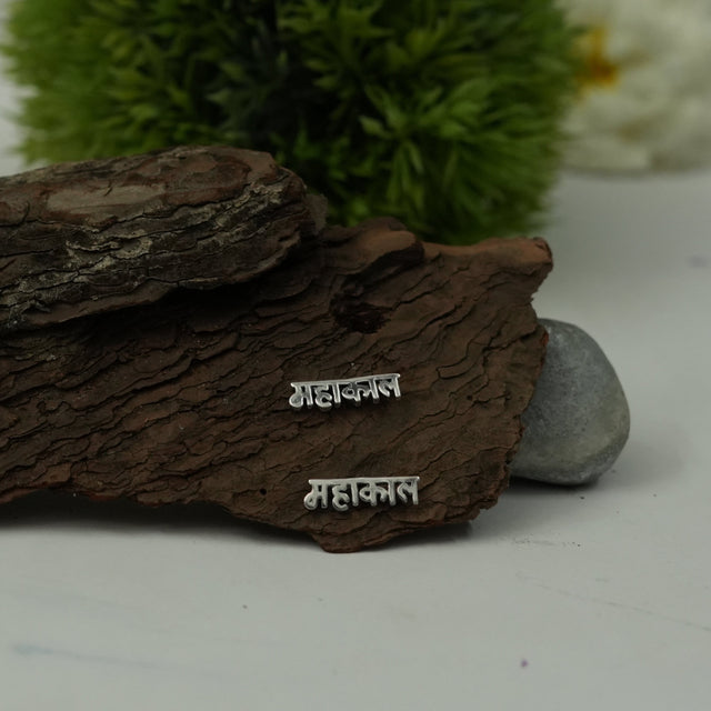 My Guru Ji silver Mahakal stud earrings featuring Devanagari script on a rustic bark background.