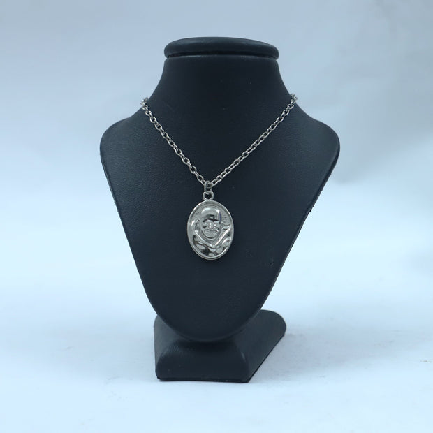 My Guru Ji silver-toned oval pendant featuring an embossed portrait of Neem Karoli Baba on a black display stand.
