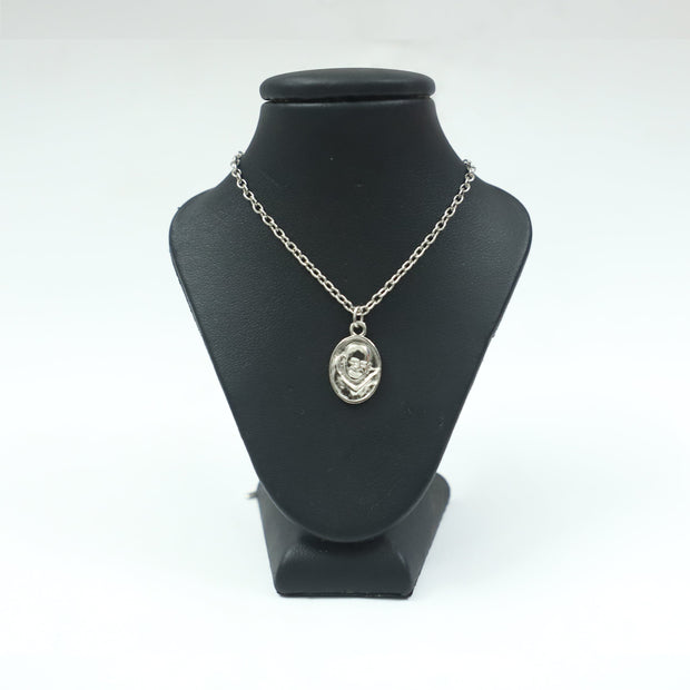 My Guru Ji silver-toned oval pendant featuring an embossed portrait of Neem Karoli Baba on a black display stand.