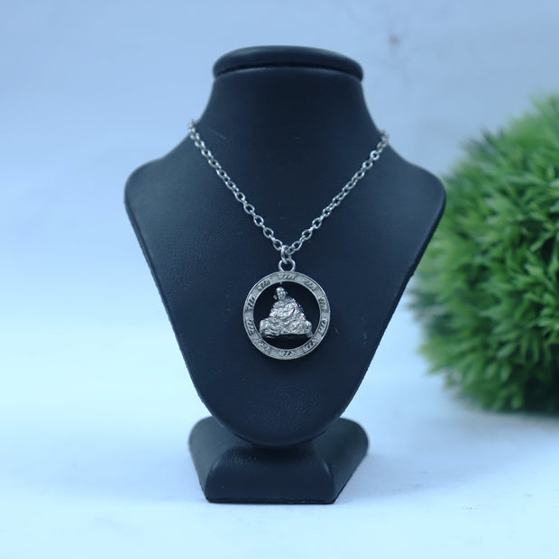 My Guru Ji silver-toned brass pendant featuring Neem Karoli Baba in blanket pose with Ram Ram engraving on a display