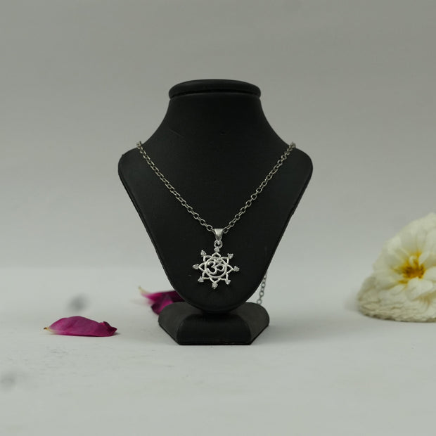 My Guru Ji silver finish Om vector chakra pendant on a black display stand with decorative flower petals