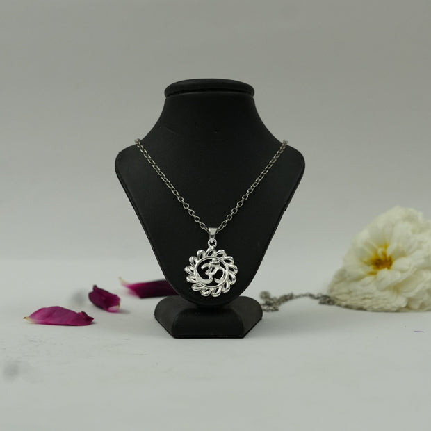 My Guru Ji silver-finish Om circle pendant on a black display stand with white flower petals for a spiritual aesthetic.