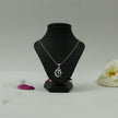 My Guru Ji silver-finish OM symbol pendant on a black display stand with a white flower and rose petal