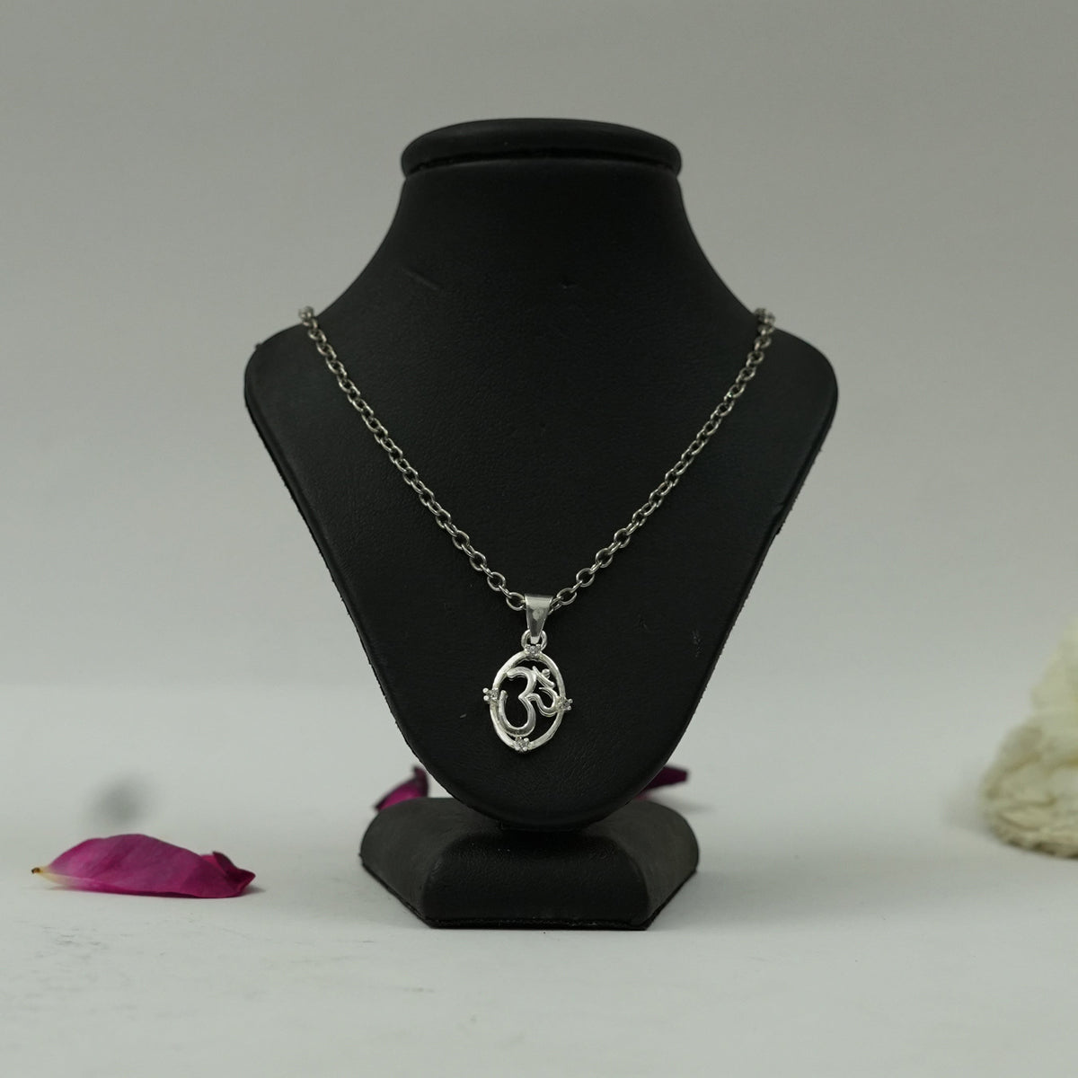My Guru Ji silver finish OM symbol pendant on a black display stand with a delicate chain