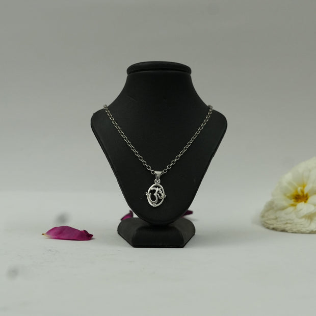 My Guru Ji silver-finish OM symbol pendant on a black display stand with a white flower and rose petal