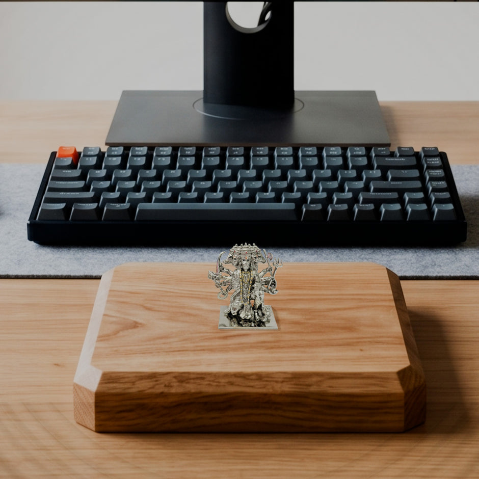 My Guru Ji silver-finish brass Panchmukhi Hanuman idol displayed on a wooden desk stand in front of a computer keyboard.