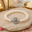 My Guru Ji Shukrana pearl bracelet featuring a silver-finish brass Guru Ji charm on a stone surface with rose petals.
