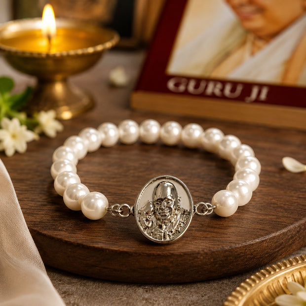 My Guru Ji pearl bracelet featuring a silver-finish brass Guru Ji charm on a wooden surface with a lit diya nearby.