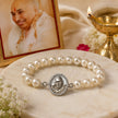 My Guru Ji pearl bracelet featuring a silver-finish brass charm with Guru Ji portrait, set on a marble surface.