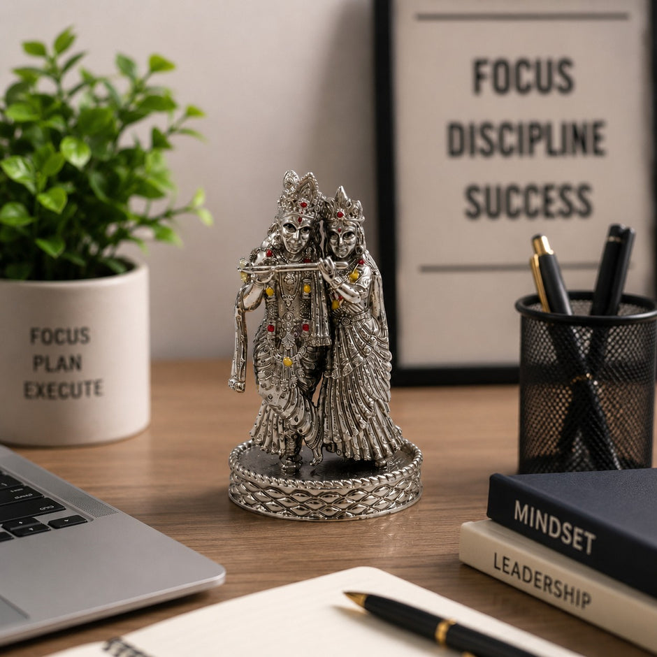 My Guru Ji Radha Krishna brass idol with silver finish, featuring intricate detailing and stone accents on a desk.