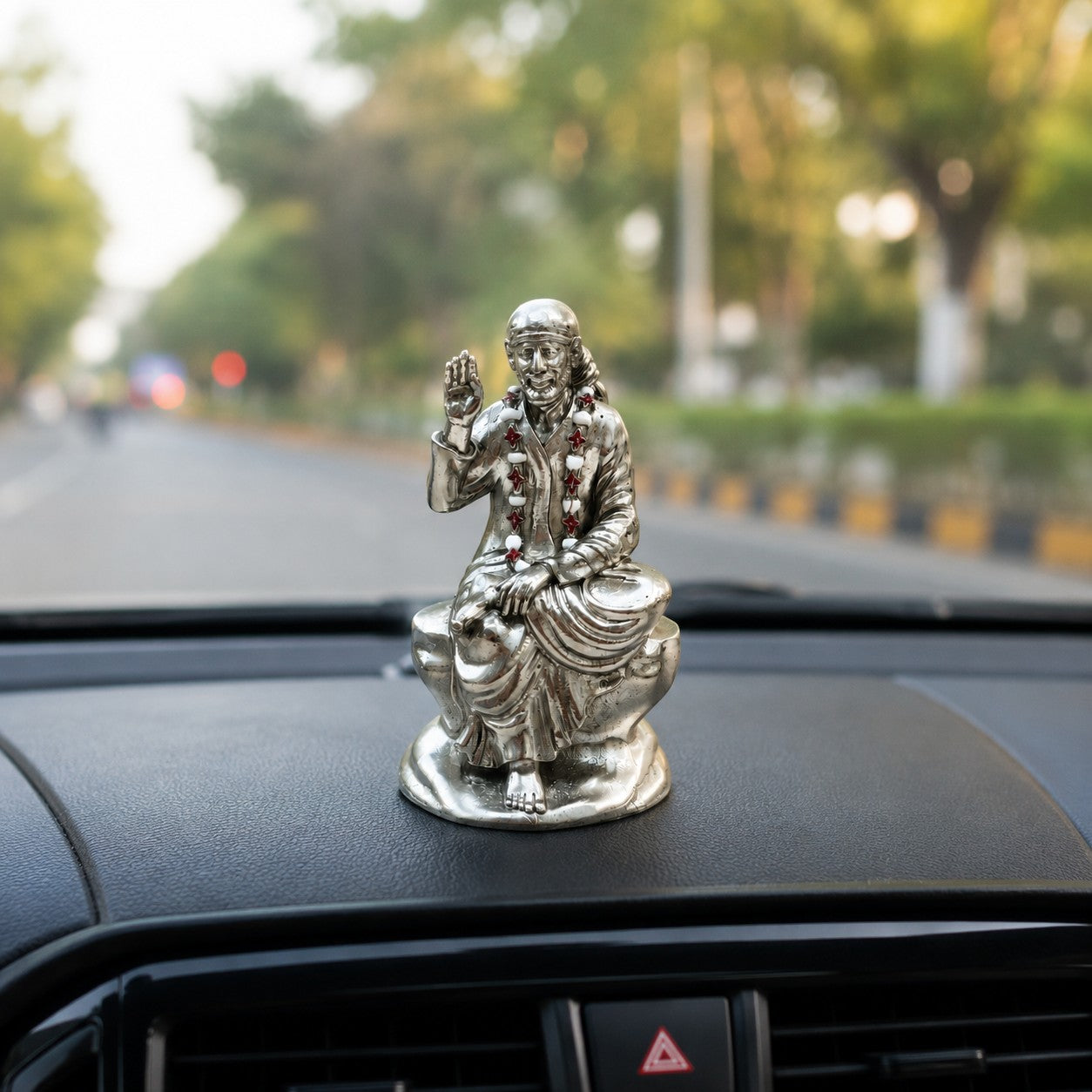 My Guru Ji silver-finished brass Shirdi Sai Baba idol seated on a car dashboard for spiritual protection and peace.