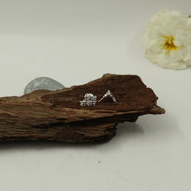 My Guru Ji Shiv Shankar stud earrings in silver finish featuring Hindi script on a rustic wooden display
