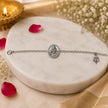 My Guru Ji silver-finished brass bracelet with a central Guru Ji portrait charm and a trishul symbol on a marble base.