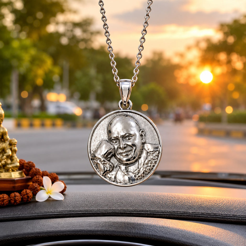 My Guru Ji round brass pendant with a silver finish, featuring an embossed portrait of Guru Ji, hanging in a car.
