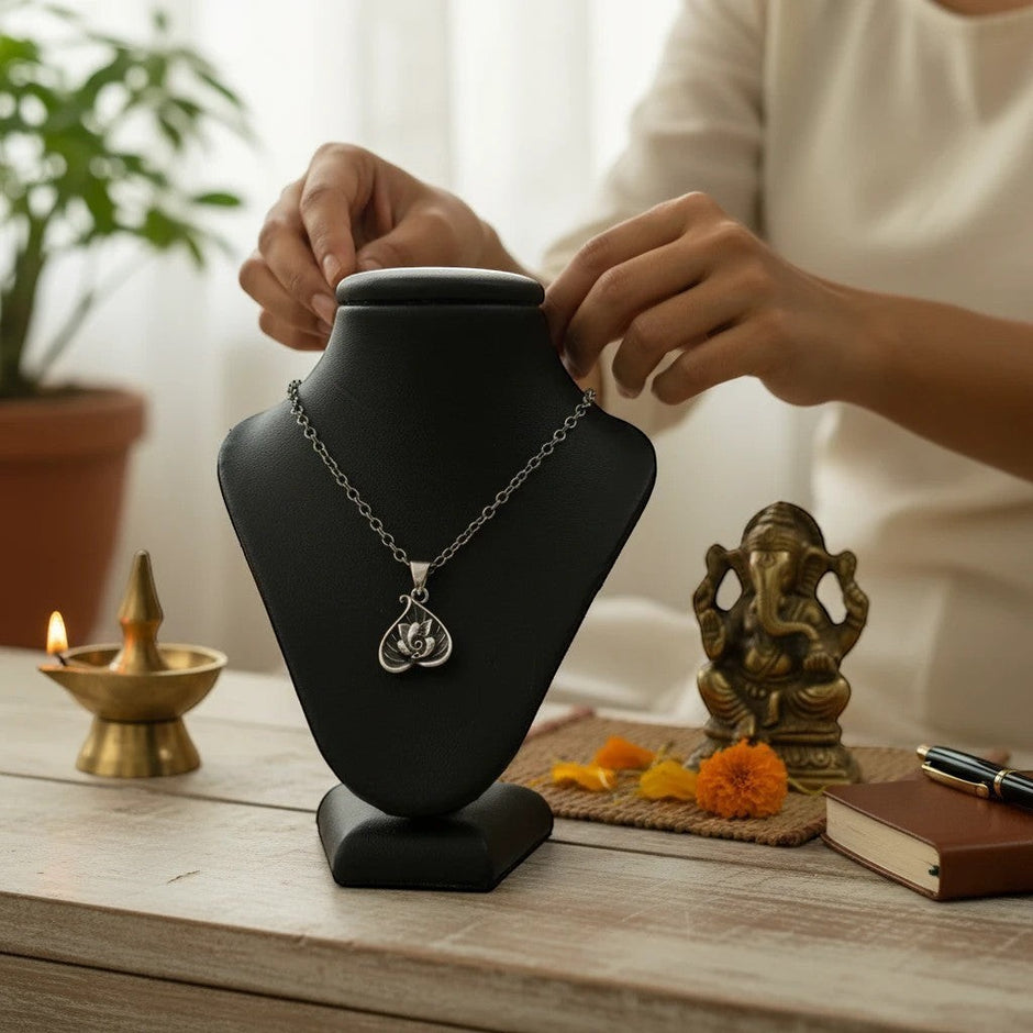 My Guru Ji silver plated brass Lord Ganesha pendant on a black display stand with a small Ganpati idol and diya.