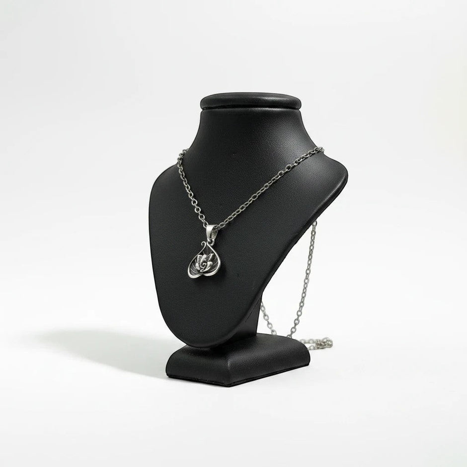 My Guru Ji silver plated brass Lord Ganesha pendant in a decorative leaf-shaped frame on a black display bust