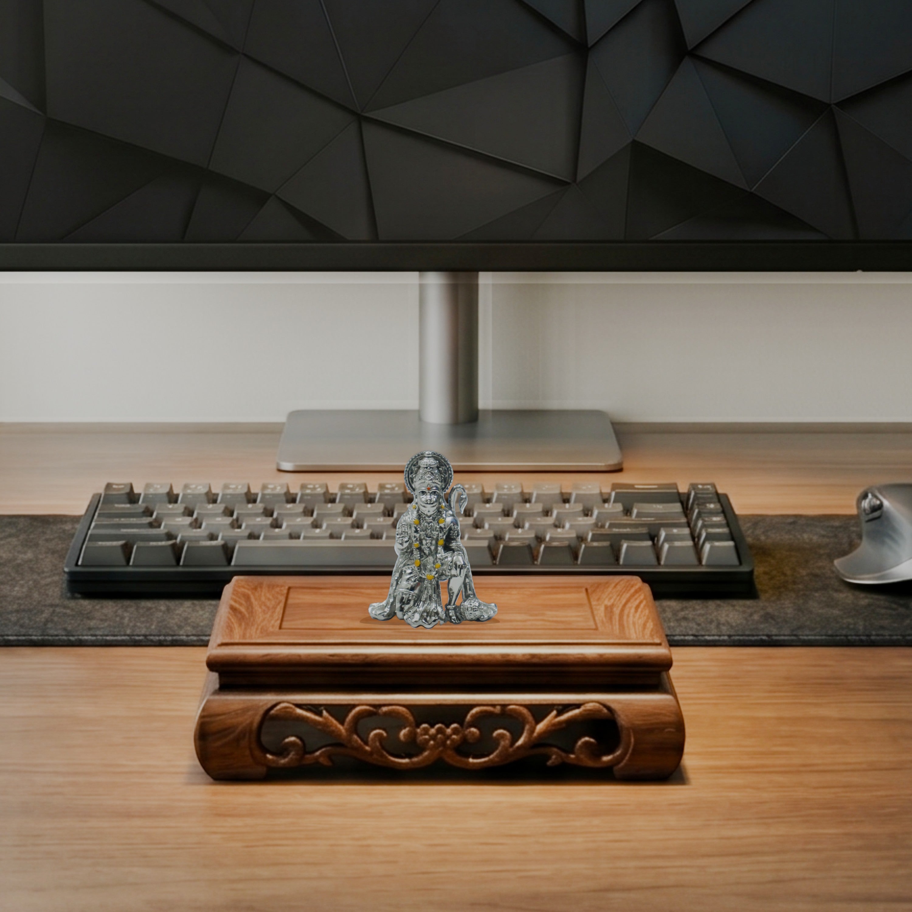 My Guru Ji silver finish brass Hanuman Ji idol in sitting posture displayed on a carved wooden base on an office desk.