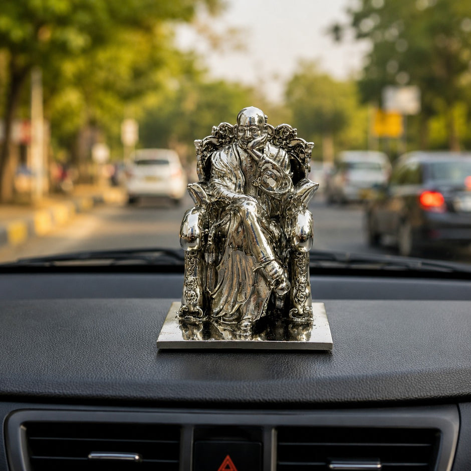 My Guru Ji silver finish brass idol of Guru Ji Bade Mandir Wale placed on a car dashboard with a blurred road view.