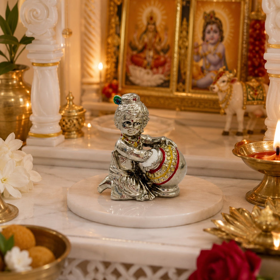 My Guru Ji silver finish brass Laddu Gopal Makhan Chor idol holding a butter pot, placed on a marble altar.