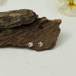 My Guru Ji silver Om stud earrings featuring a polished finish on a rustic piece of tree bark