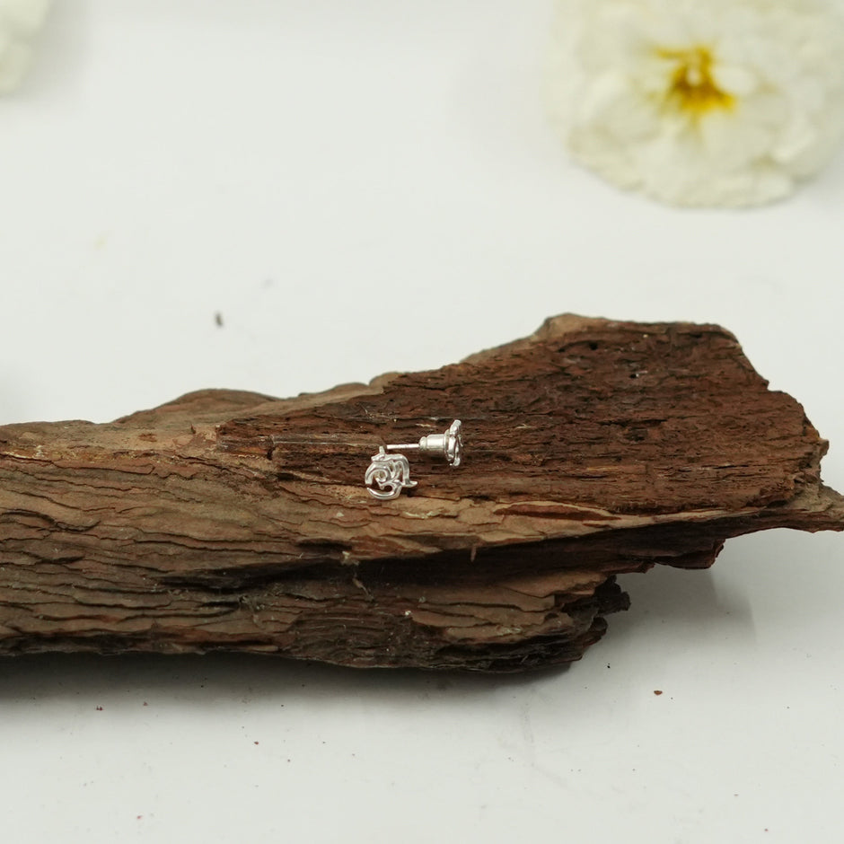 My Guru Ji silver Om symbol stud earrings with a polished finish, displayed on a piece of natural wood.