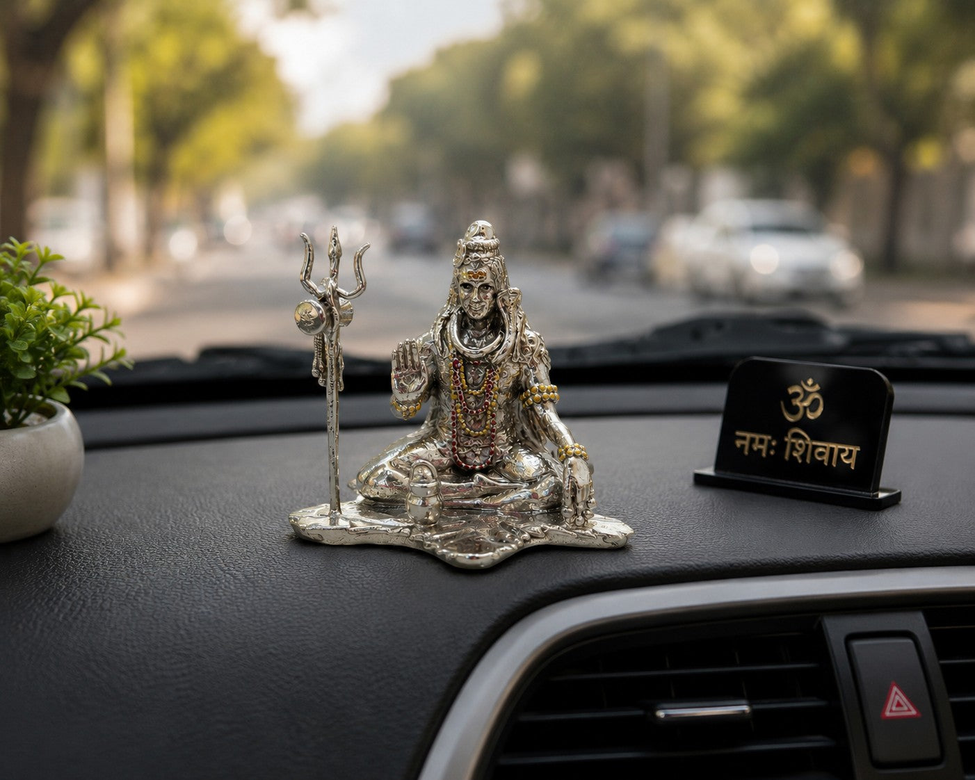 My Guru Ji silver finish brass Lord Shiva idol with Trishul and Shivling displayed on a car dashboard.