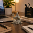My Guru Ji silver finish brass Lord Shiva idol in meditative pose with Trishul on a desk near a laptop and books.