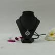 My Guru Ji silver finish Swastik pendant with vector chakra design on a black display stand with flower petals