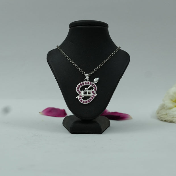 My Guru Ji Tamil Om pendant in silver-finished brass with pink stone accents displayed on a black jewelry bust.
