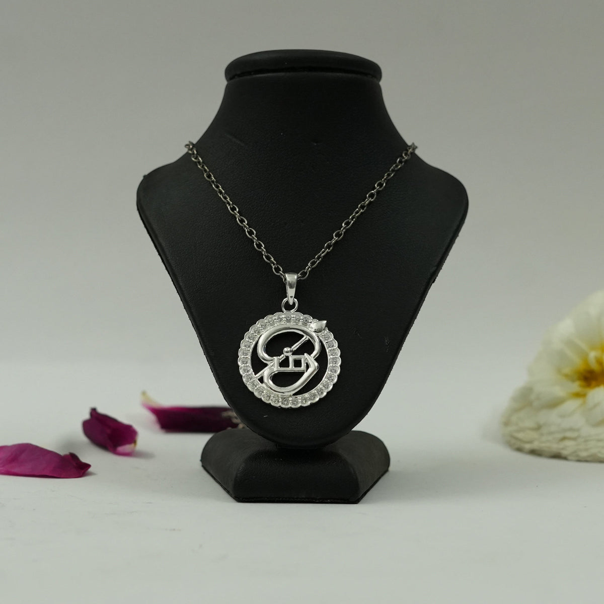 My Guru Ji silver-finish Tamil OM pendant featuring a circular frame with crystal accents on a black display bust.