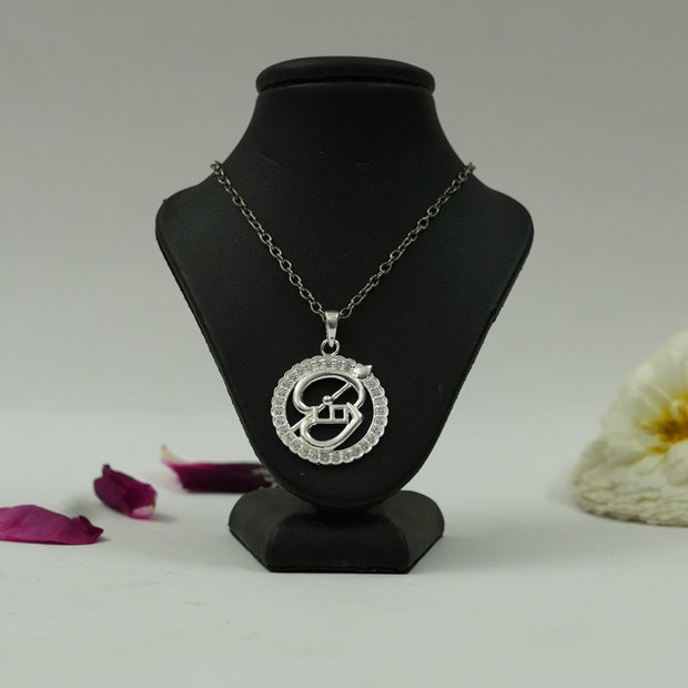 My Guru Ji silver-finish Tamil OM pendant featuring a circular frame with crystal accents on a black display bust.